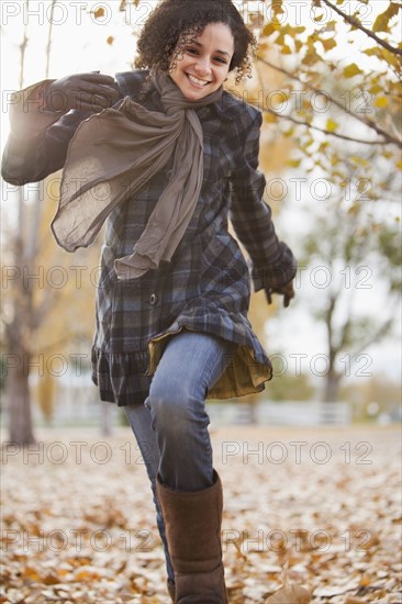 Caucasian woman running in autumn leaves