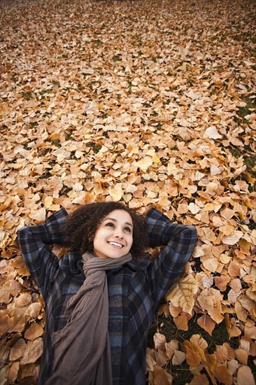 Caucasian woman laying in autumn leaves