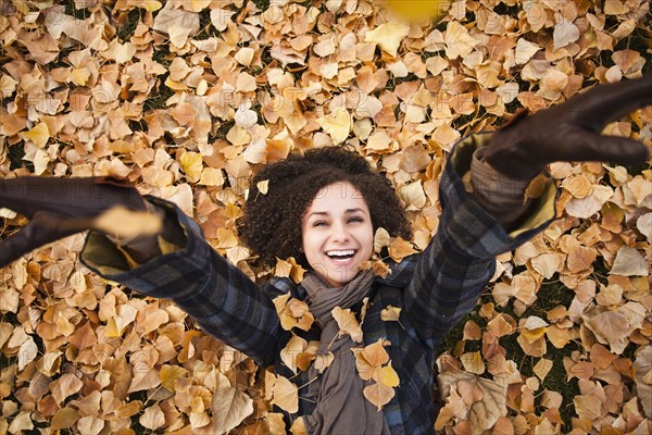 Caucasian woman laying in autumn leaves