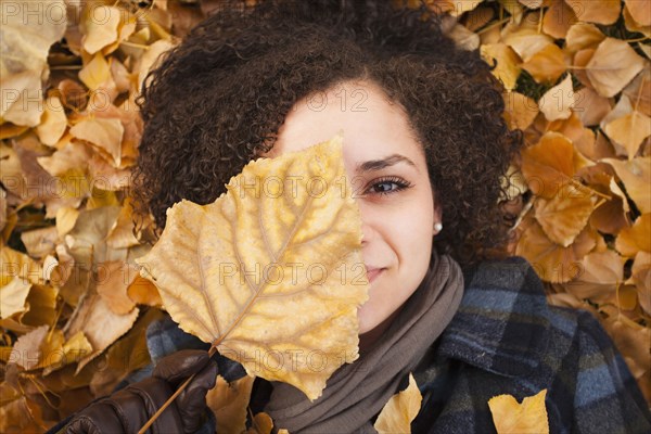 Caucasian woman laying in autumn leaves