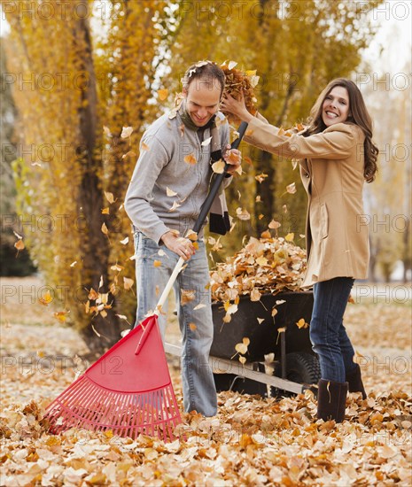 Caucasian couple raking autumn leaves