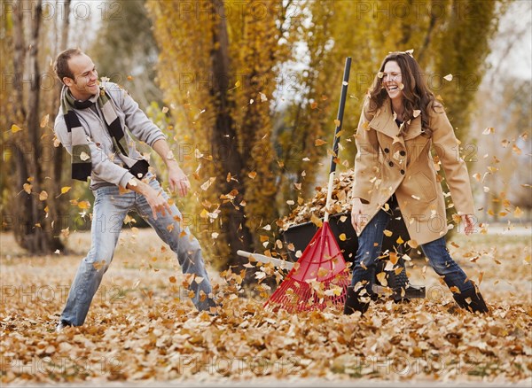 Caucasian couple raking autumn leaves