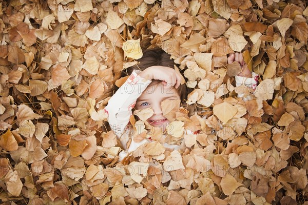 Caucasian girl laying in autumn leaves