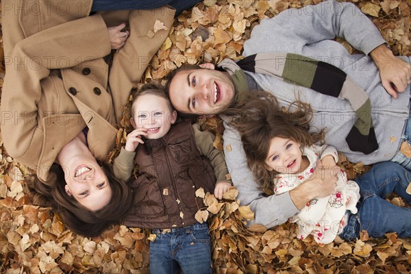 Caucasian family laying in autumn leaves