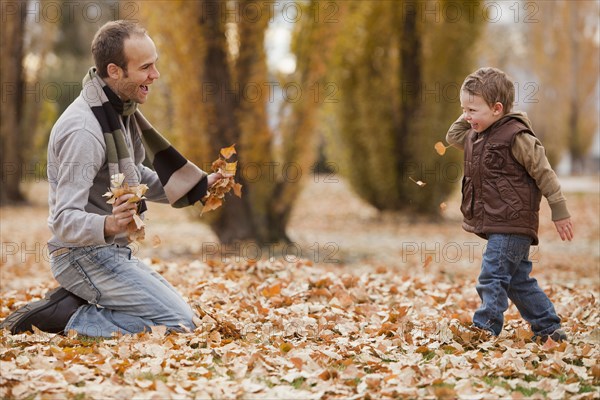 Caucasian father and son playing in autumn leaves