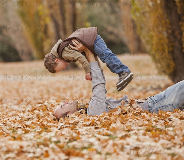 Caucasian father and son playing in autumn leaves