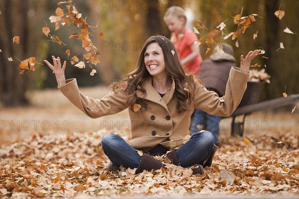 Caucasian woman playing in autumn leaves