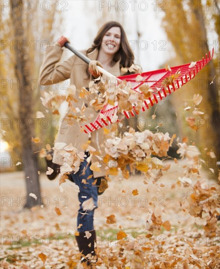 Caucasian woman raking autumn leaves