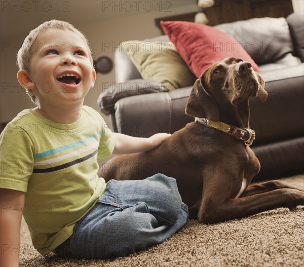 Caucasian boy sitting on floor with dog