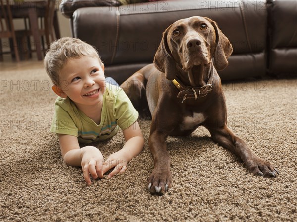 Caucasian boy sitting on floor with dog