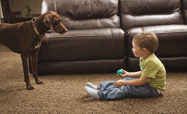 Caucasian boy playing ball with dog