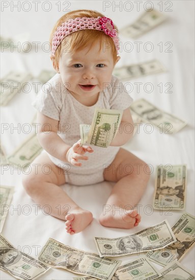 Caucasian baby girl playing with twenty dollar bills