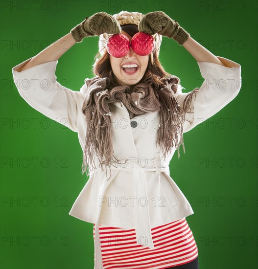 Mixed race woman holding Christmas ornaments in front of her face