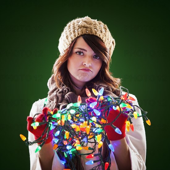 Mixed race woman holding tangle of Christmas lights