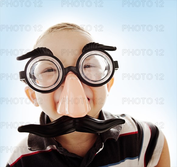 Caucasian boy in funny mustache mask