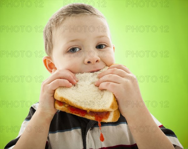 Caucasian boy eating peanut butter and jelly sandwich