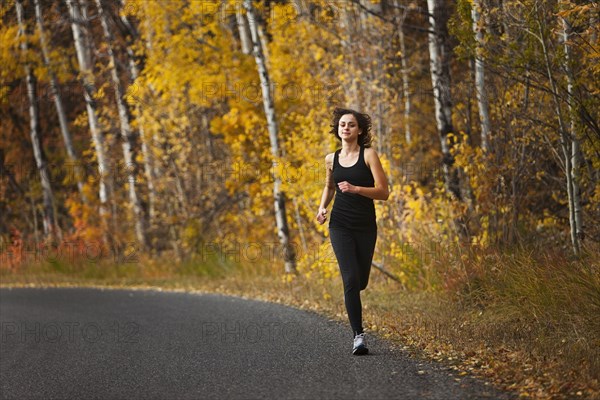 Caucasian woman running along autumn road
