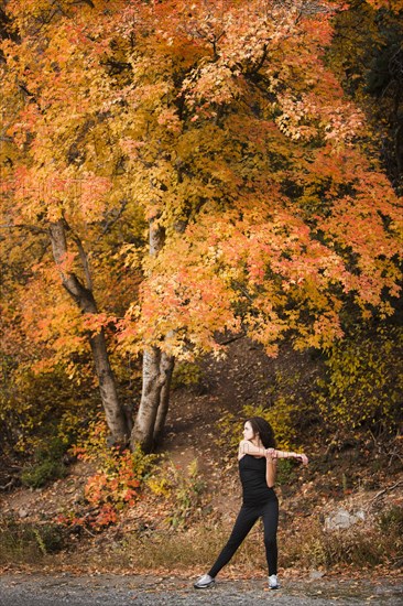 Caucasian woman stretching in autumn road