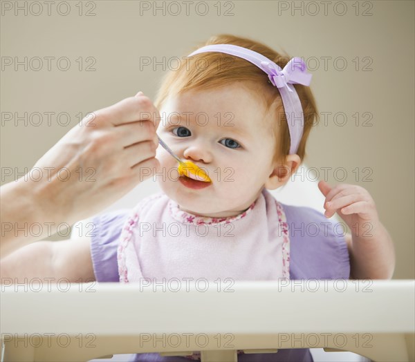 Caucasian mother feeding baby girl