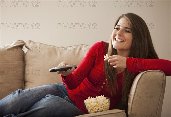 Caucasian woman watching television and eating popcorn