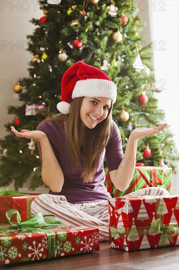 Caucasian woman in Santa hat sitting with Christmas gifts