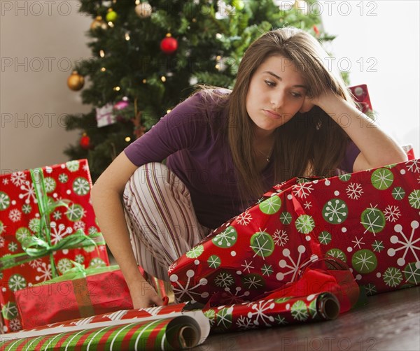 Bored Caucasian woman wrapping Christmas gifts