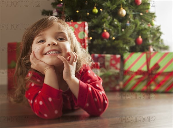 Caucasian girl laying on floor near Christmas tree