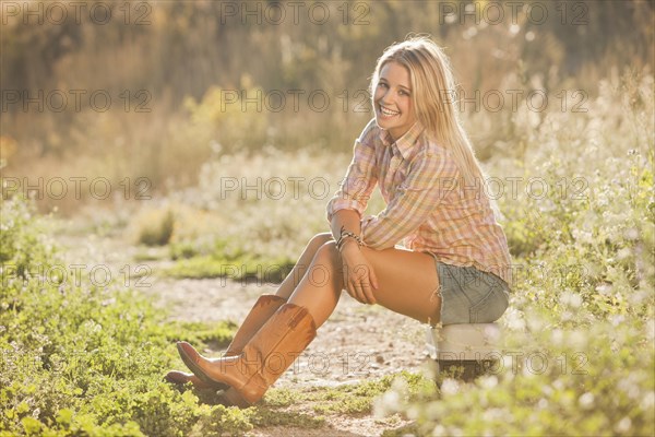 Caucasian woman sitting on tackle box in field
