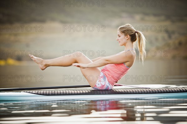 Caucasian woman practicing yoga on paddle board