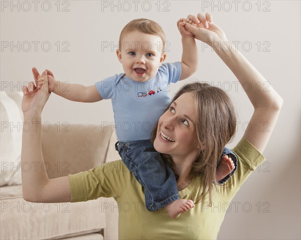 Caucasian mother carrying son on her shoulders