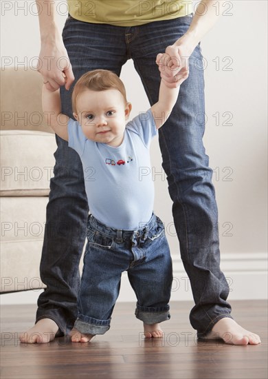 Caucasian mother helping son learn to walk