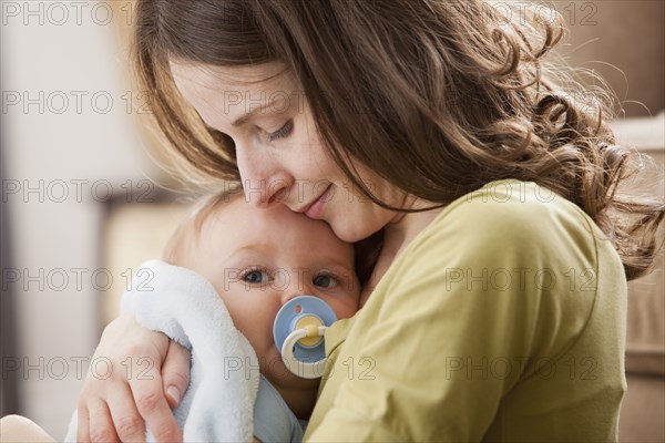 Caucasian baby boy with pacifier in mother's arms