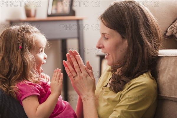 Caucasian mother and daughter playing clapping game