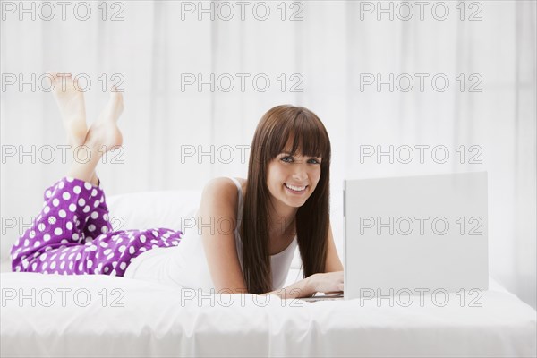 Caucasian woman using laptop on bed