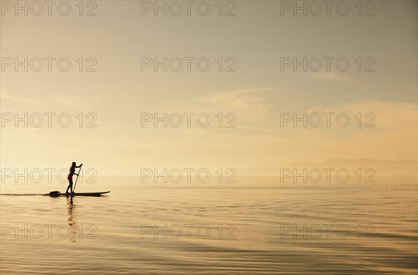 Caucasian woman standing on paddle board