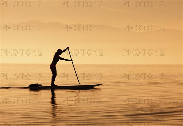 Caucasian woman standing on paddle board