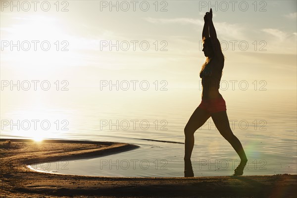 Caucasian woman practicing yoga on beach