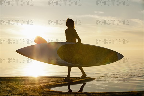 Caucasian man carrying paddle board on beach
