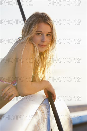 Caucasian woman leaning on paddle board