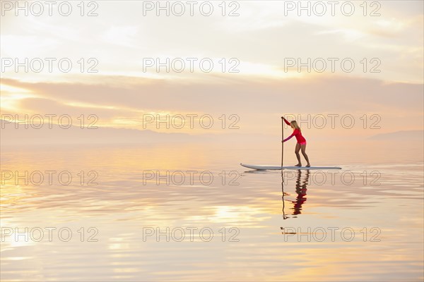 Caucasian woman standing on paddle board