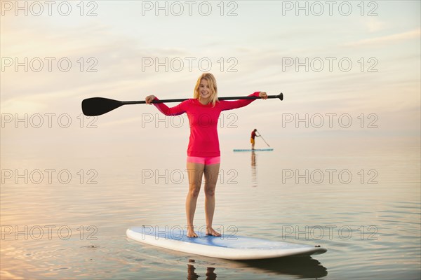 Caucasian woman standing on paddle board