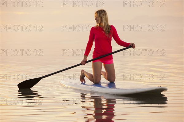 Caucasian woman kneeling on paddle board