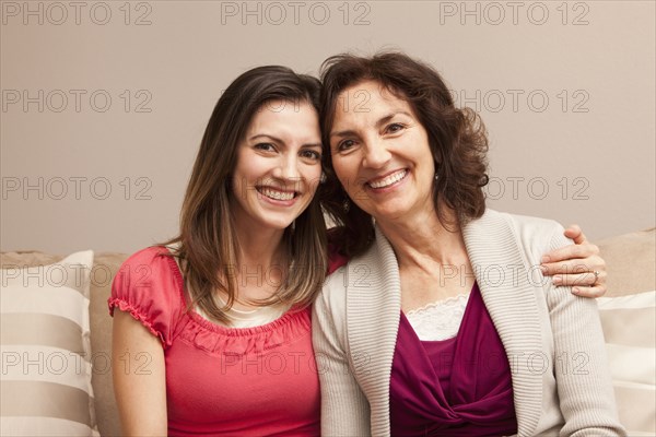 Caucasian mother and daughter sitting on sofa