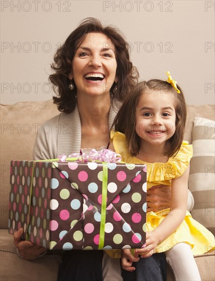 Caucasian grandmother and granddaughter holding gift