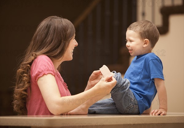 Caucasian mother putting bandage on son's knee