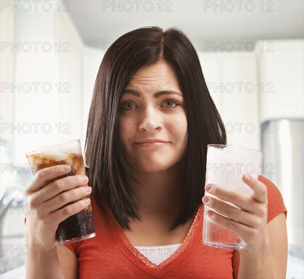 Caucasian woman holding glasses of soda and water