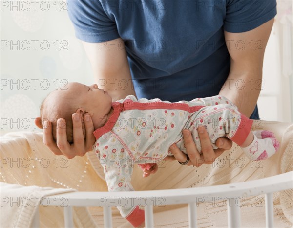 Caucasian father lifting baby girl from crib