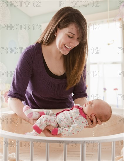 Caucasian mother lifting baby girl from crib