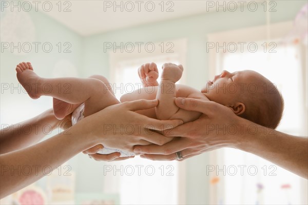 Caucasian mother and father holding baby girl