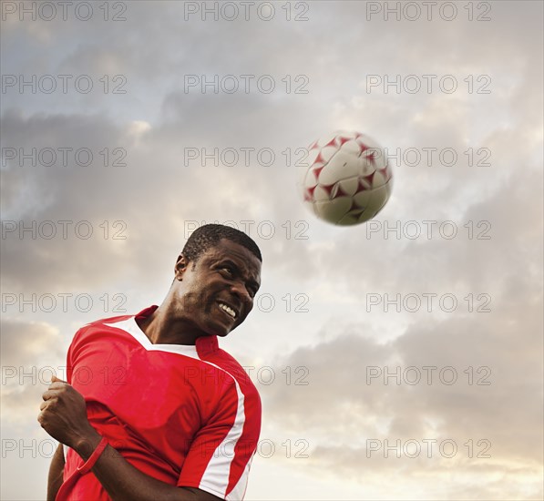 Black soccer player heading the ball